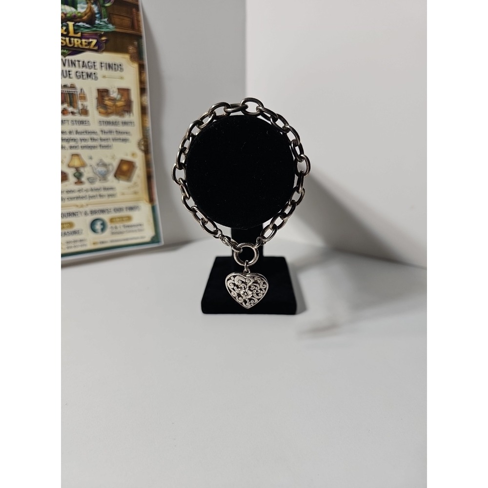 silver-toned charm bracelet with an intricate floral heart pendant